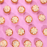 Vegan Vanilla Cupcakes with smooth plant-based icing and rainbow sprinkles on pink background by Crumbs & Doilies